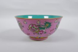 A Chinese polychrome porcelain rice bowl, decorated with temple lions on a pink field, inscription