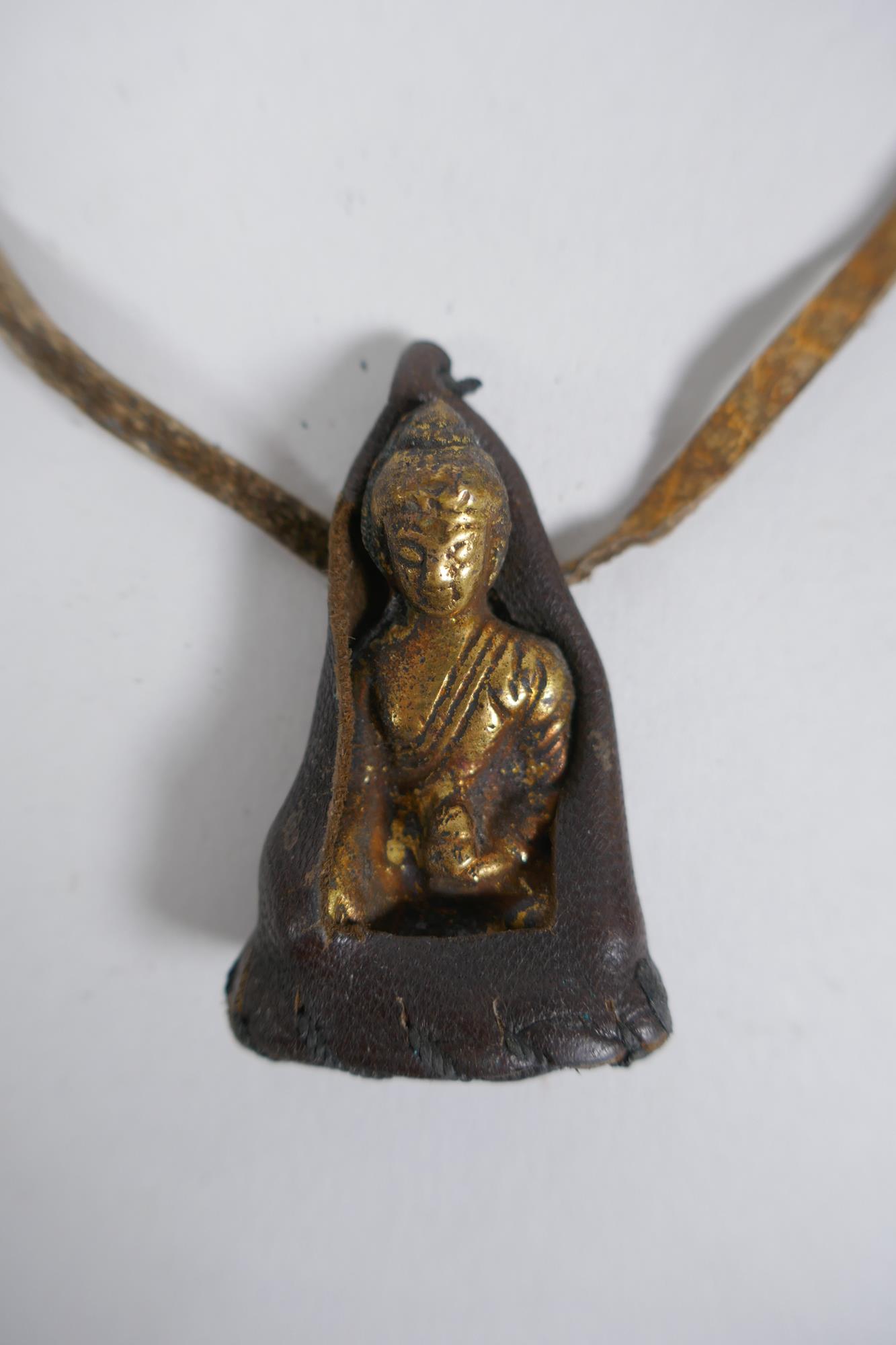 An antique Tibetan bronze Buddha amulet in a leather sheath, 5cm - Image 2 of 2