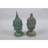 A pair of bronze Buddha's heads with green patina, mounted on a metal stand, 16.5cm high