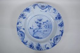 A C19th Delft blue and white tin glazed charger decorated with a riverside landscape, AF, 37cm