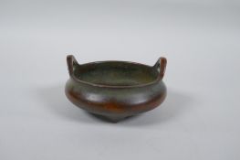 A Chinese bronze censer with two phoenix eye handles and tripod supports, impressed seal mark to