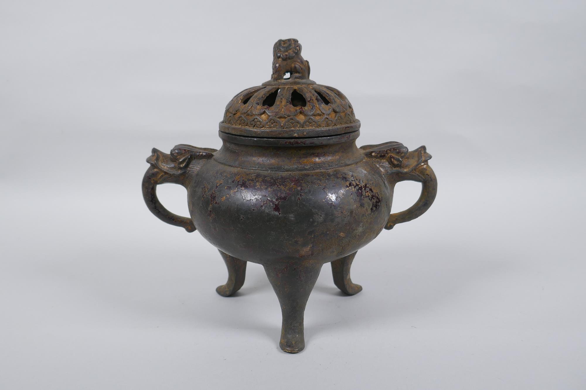 A Chinese gilt bronze censer and pierced cover, raised on tripod supports, with two dragon mask