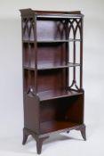 A mahogany dwarf bookcase with waterfall front and pierced fret sides, raised on swept supports,