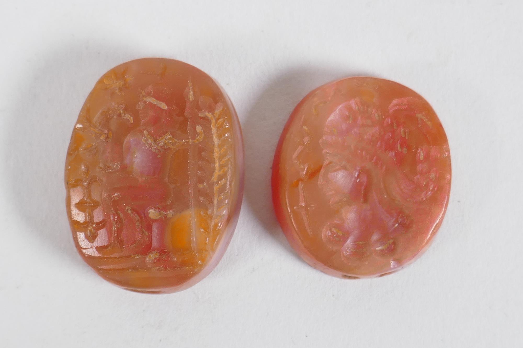 Two Persian amber agate intaglio beads with figural decoration, 2 x 2.5cm