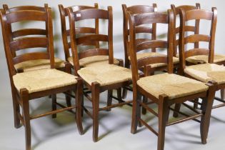 A set of eight French country style chairs with rush seats and ladder backs, raised on shaped