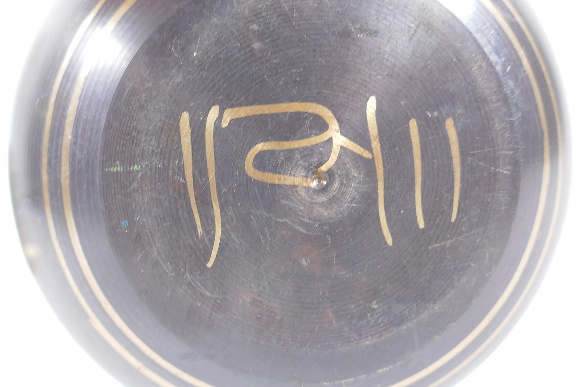 A Tibetan bronze singing bowl with script decoration and wood beater, and a brass ceremonial bell - Image 4 of 5