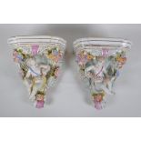 A pair of Dresden style porcelain wall shelves decorated with putti and flowers, 24cm high