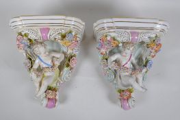 A pair of Dresden style porcelain wall shelves decorated with putti and flowers, 24cm high