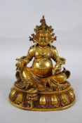 An antique Sino Tibetan heavy gilt bronze figure of Jambhala seated on a lotus throne, double