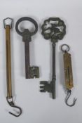 Two antique Salter brass spring balance scales, and two cast iron oversized keys, largest 35cm