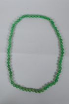 An apple green jade bead necklace, 82cm long