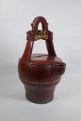 An antique Chinese red lacquered wood basket with spout and carved handle, 40cm high