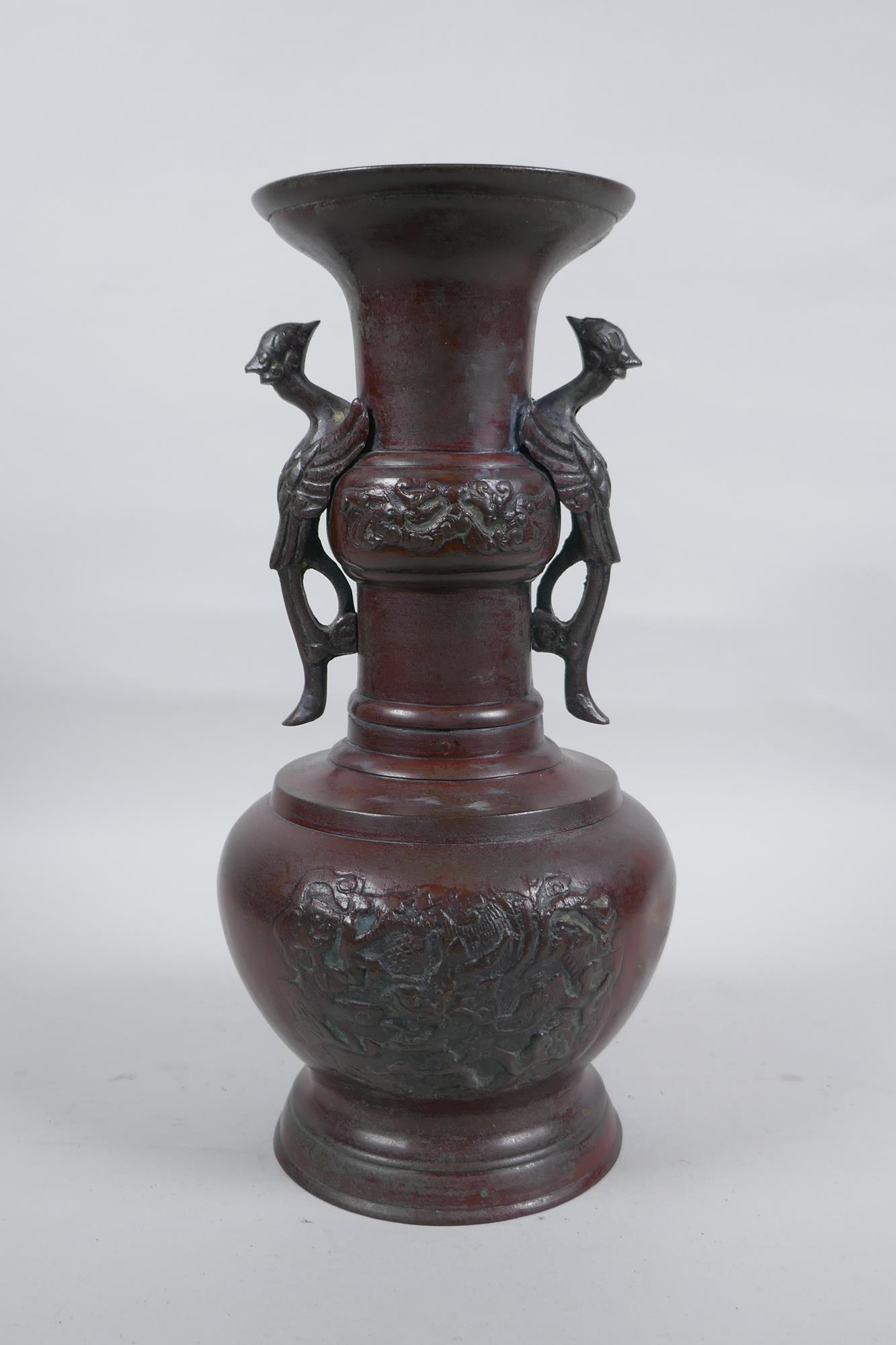 A Chinese bronze vase with two phoenix handles and raised panels depicting dragons, 30cm high