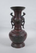 A Chinese bronze vase with two phoenix handles and raised panels depicting dragons, 30cm high