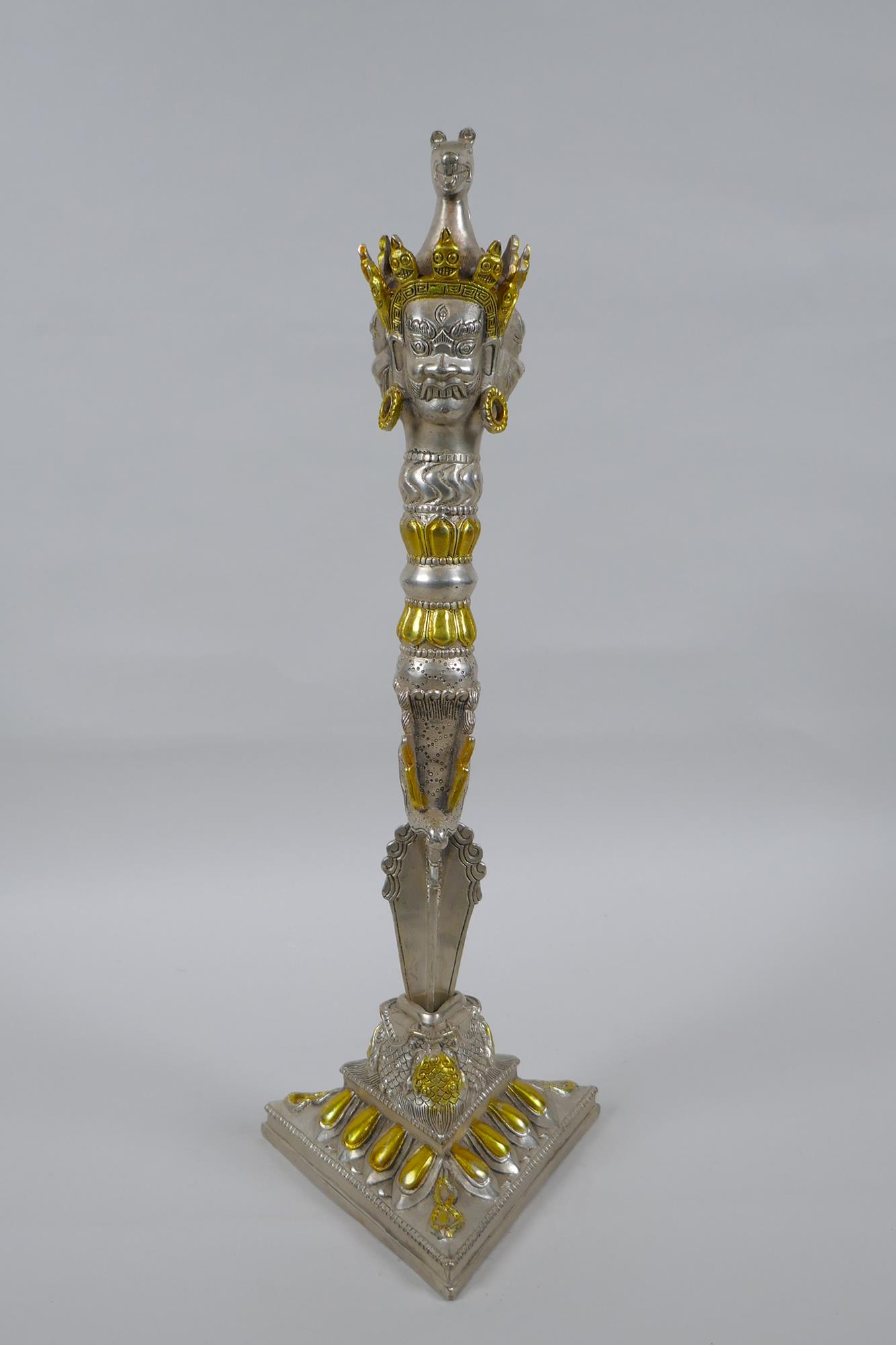 A Tibetan ceremonial metal phurba and stand with gilt metal highlights and wrathful deity masks to