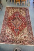 An antique Persian red and cream ground Heriz full pile carpet with black borders, 210 x 296cm
