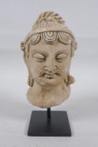 A Gandahar style plaster bust, on a display stand, 18cm high