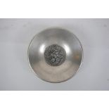 A Chinese white metal dish with raised phoenix and dragon decoration, character mark to base, 14cm