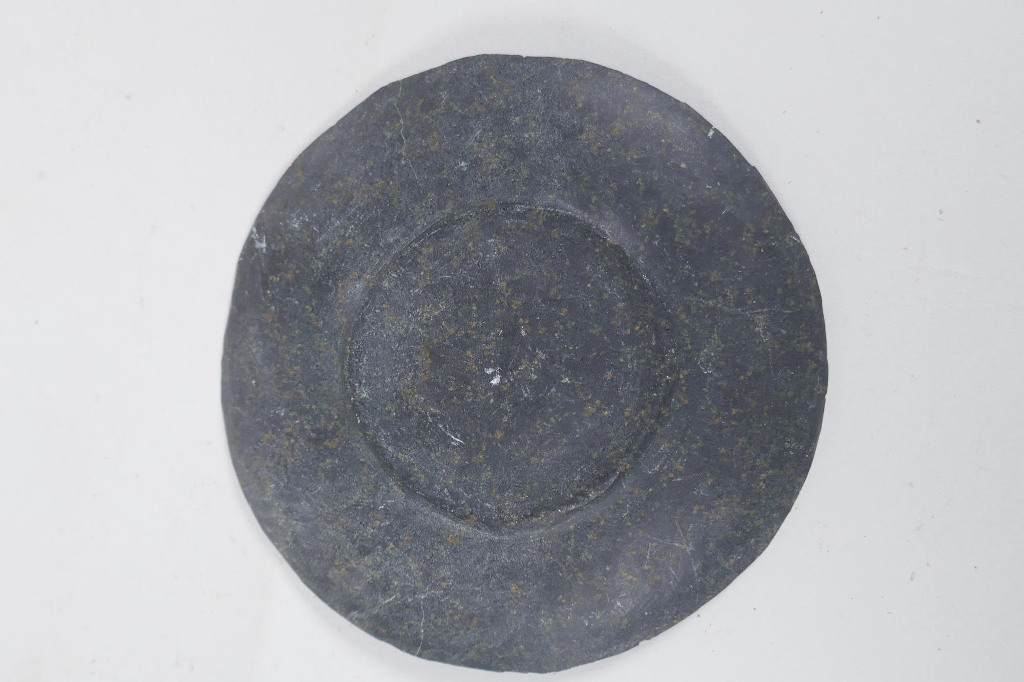 A Persian carved stone dish depicting a lion slayer, 15cm diameter - Image 2 of 2