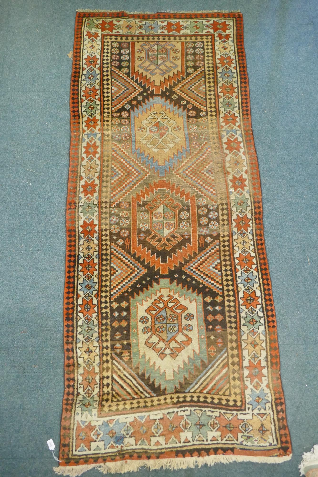 A multi colour ground Kurdish Kazak wool runner with a geometric medallion design on a brown