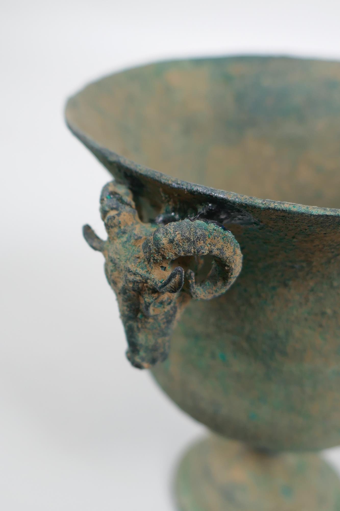 An antique metal goblet with rams head mounts, and green patina, 12cm high - Image 4 of 5