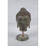 A bronze Buddha head bust on a metal base, with green patina, 26cm high