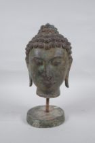 A bronze Buddha head bust on a metal base, with green patina, 26cm high