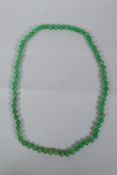 An apple green jade bead necklace, 82cm long