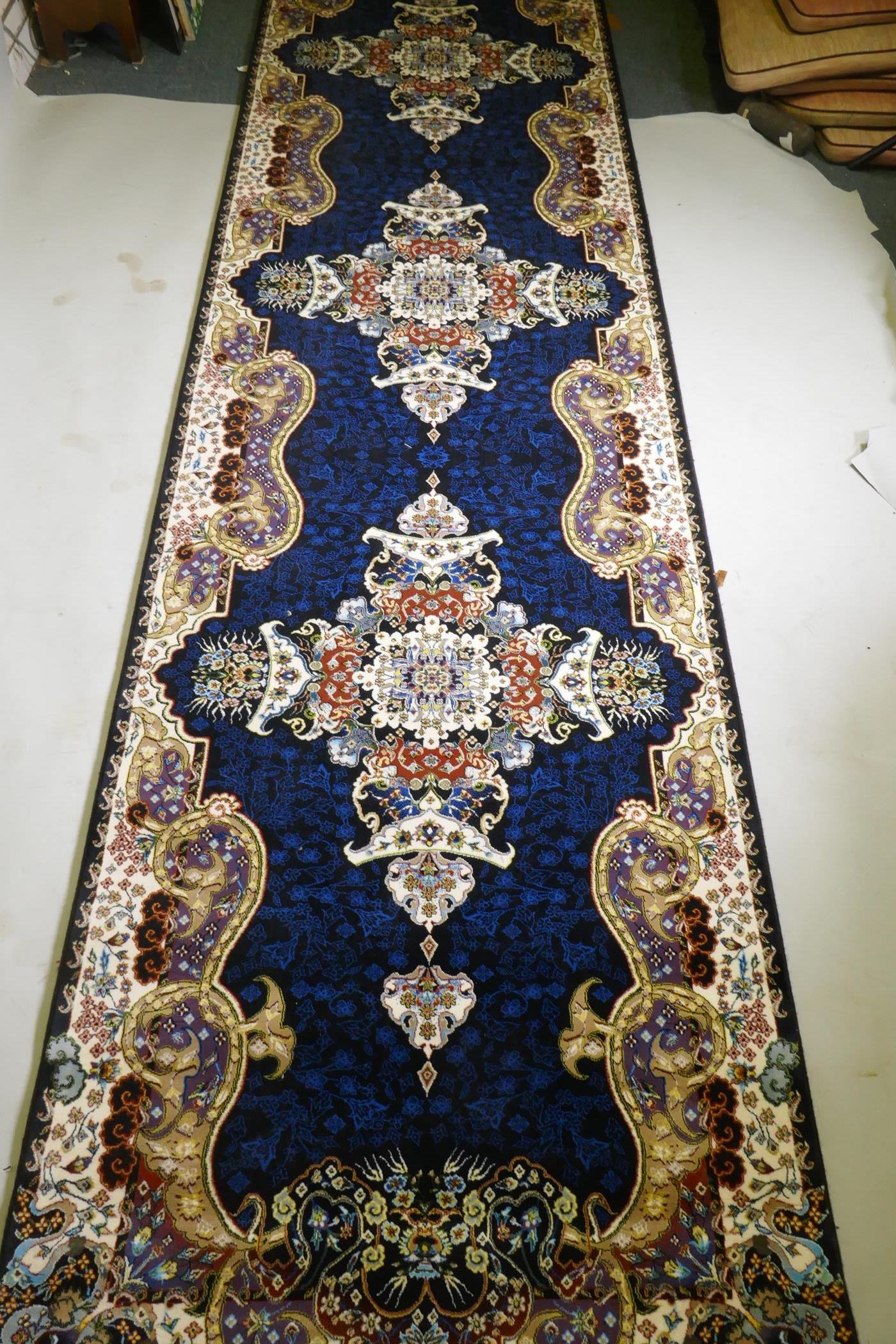 An Iranian fine woven runner with floral medallion design on a deep blue field, 100x  410cm