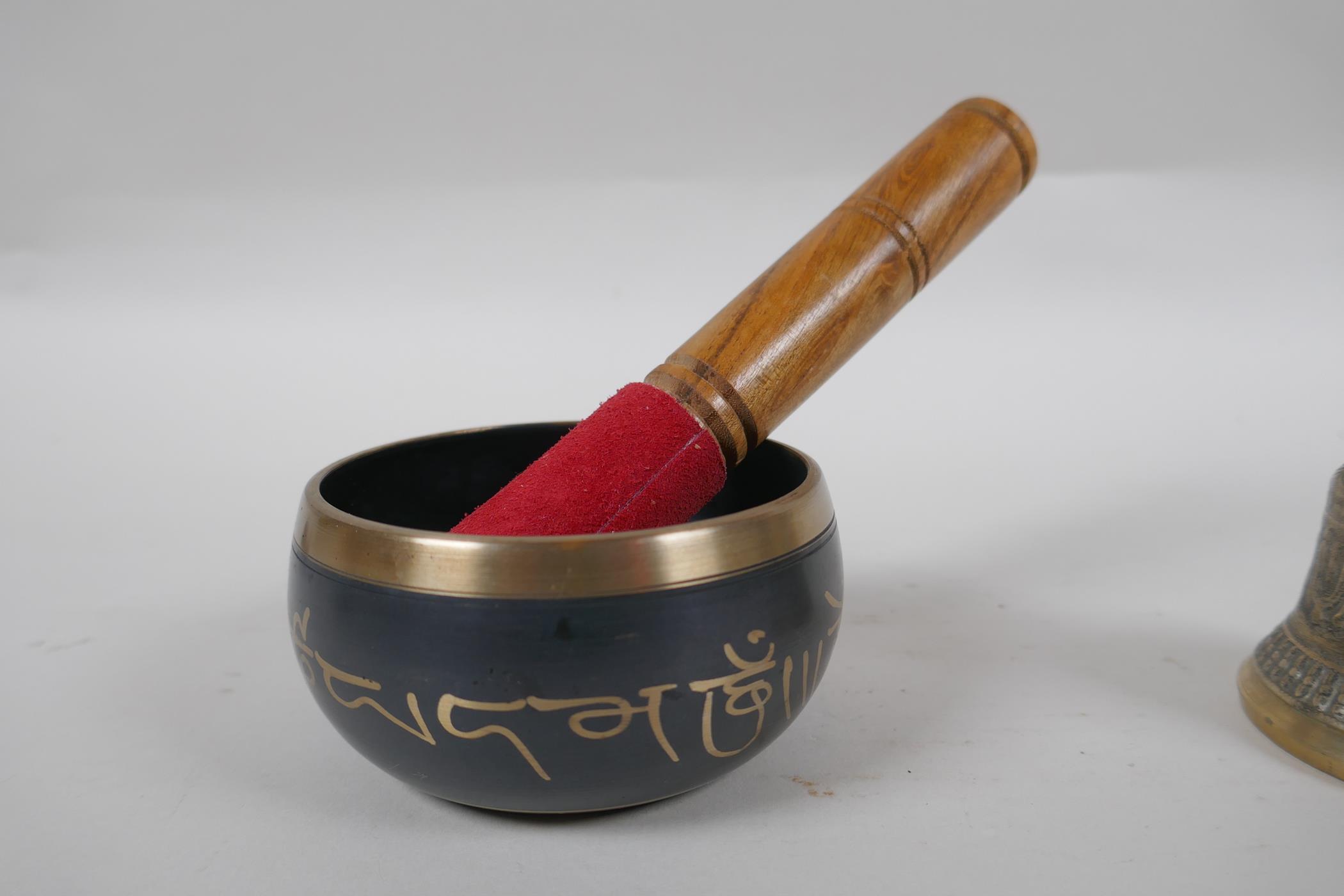 A Tibetan bronze singing bowl and beater with script decoration, a brass ceremonial bell with - Image 2 of 5