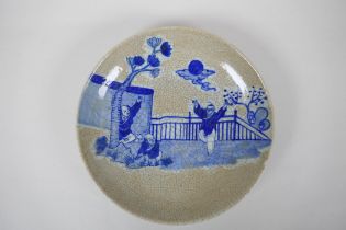 A Chinese blue and white crackleware dish decorated with boys playing in a garden, 26cm diameter