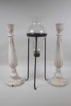 A pair of turned and distressed pricket candlesticks, and a wrought iron and glass hurricane vase,