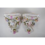 A pair of Dresden style porcelain wall shelves decorated with putti and flowers, 24cm high