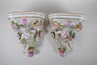 A pair of Dresden style porcelain wall shelves decorated with putti and flowers, 24cm high