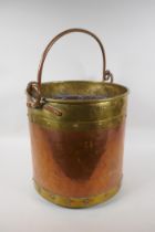 An antique brass and copper riveted coal bucket, 33cm high x 31cm diameter