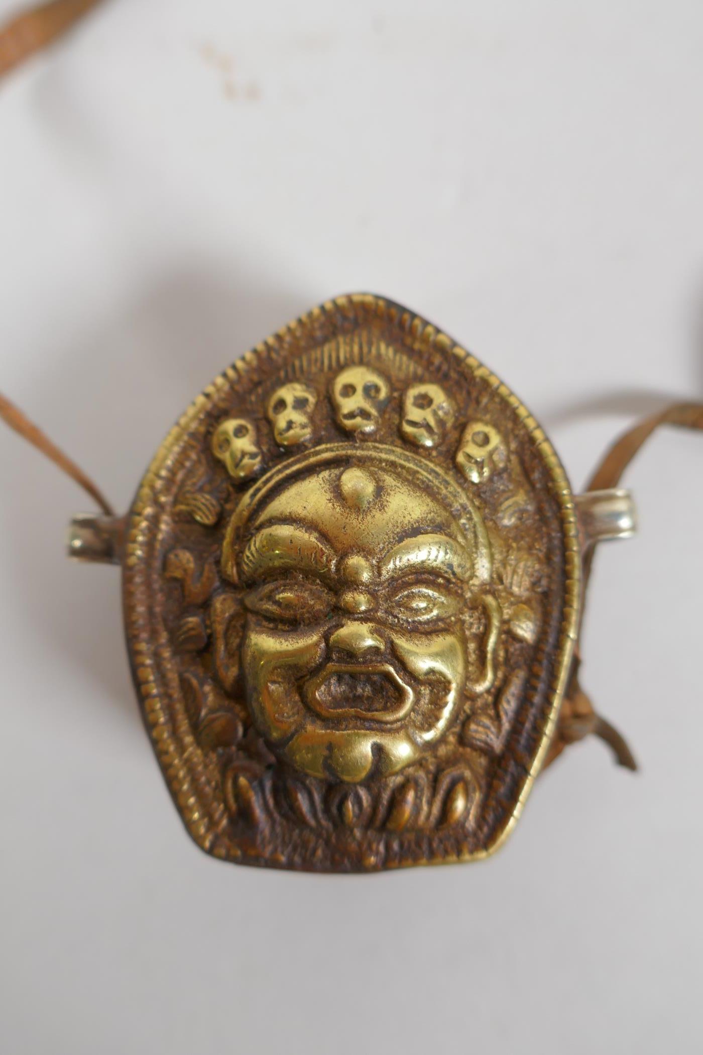 A Tibetan copper and brass Gau box, with repousse wrathful deity mask decoration, 4 x 6cm