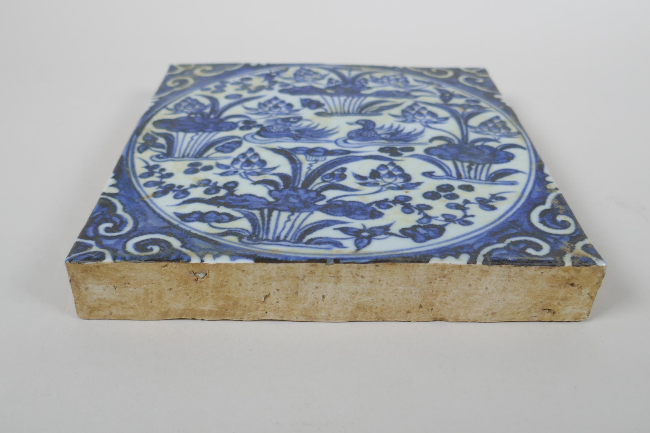 A Chinese blue and white porcelain temple tile decorated with waterfowl in a lotus pond, 20 x 20cm - Image 2 of 2