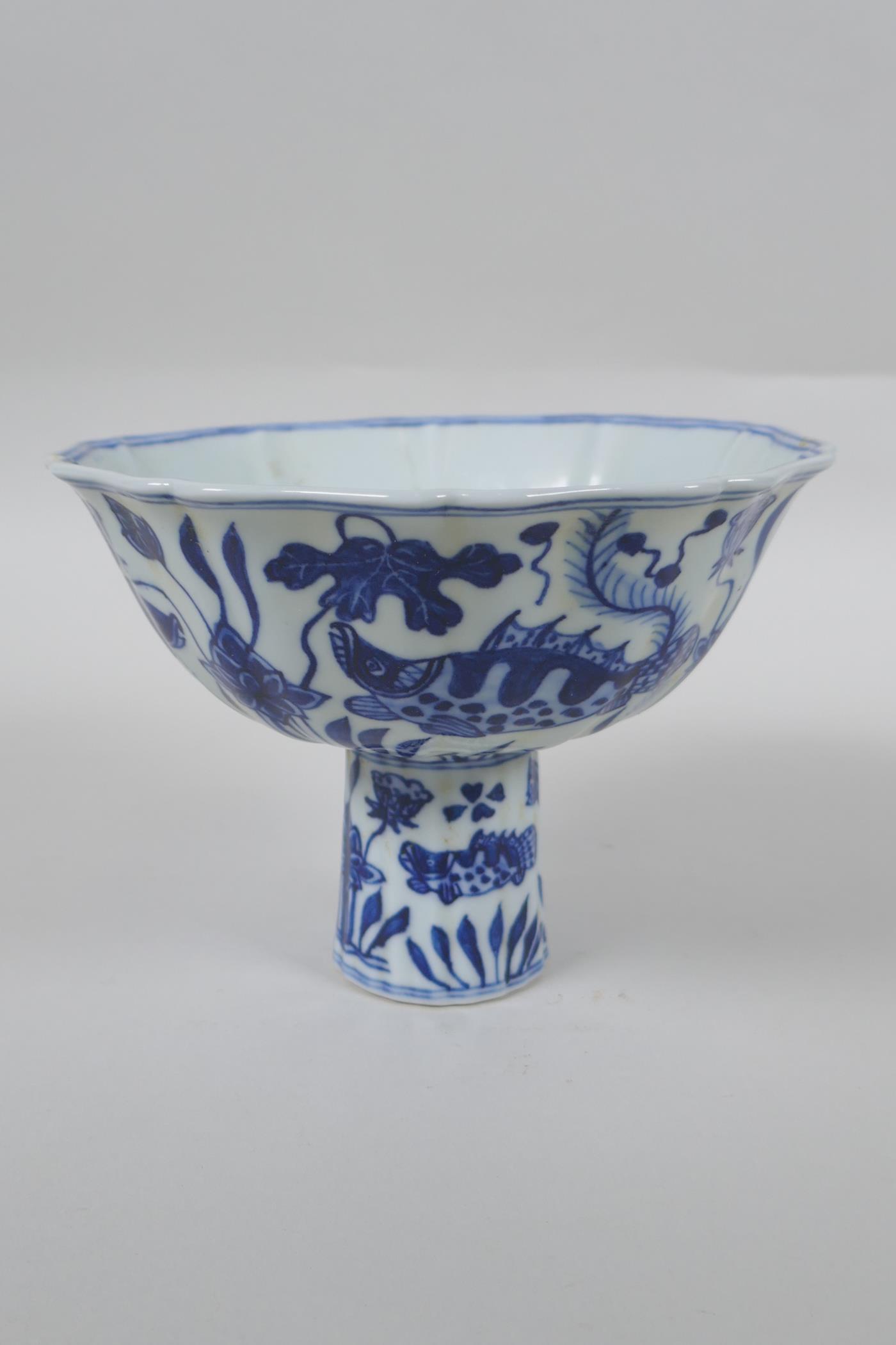 A Chinese blue and white porcelain stem bowl of lobed form decorated with carp in a lotus pond,