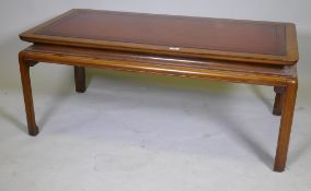 A Chinese style walnut coffee table with inset tooled leather top, 126 x 65 x 52cm