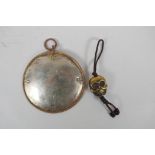 A Tibetan silvered metal mirror pendant and a bronze skull pendant, 10cm diameter