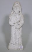 An antique carved weathered marble flat back figure of a barefoot monk holding a book, 50cm high