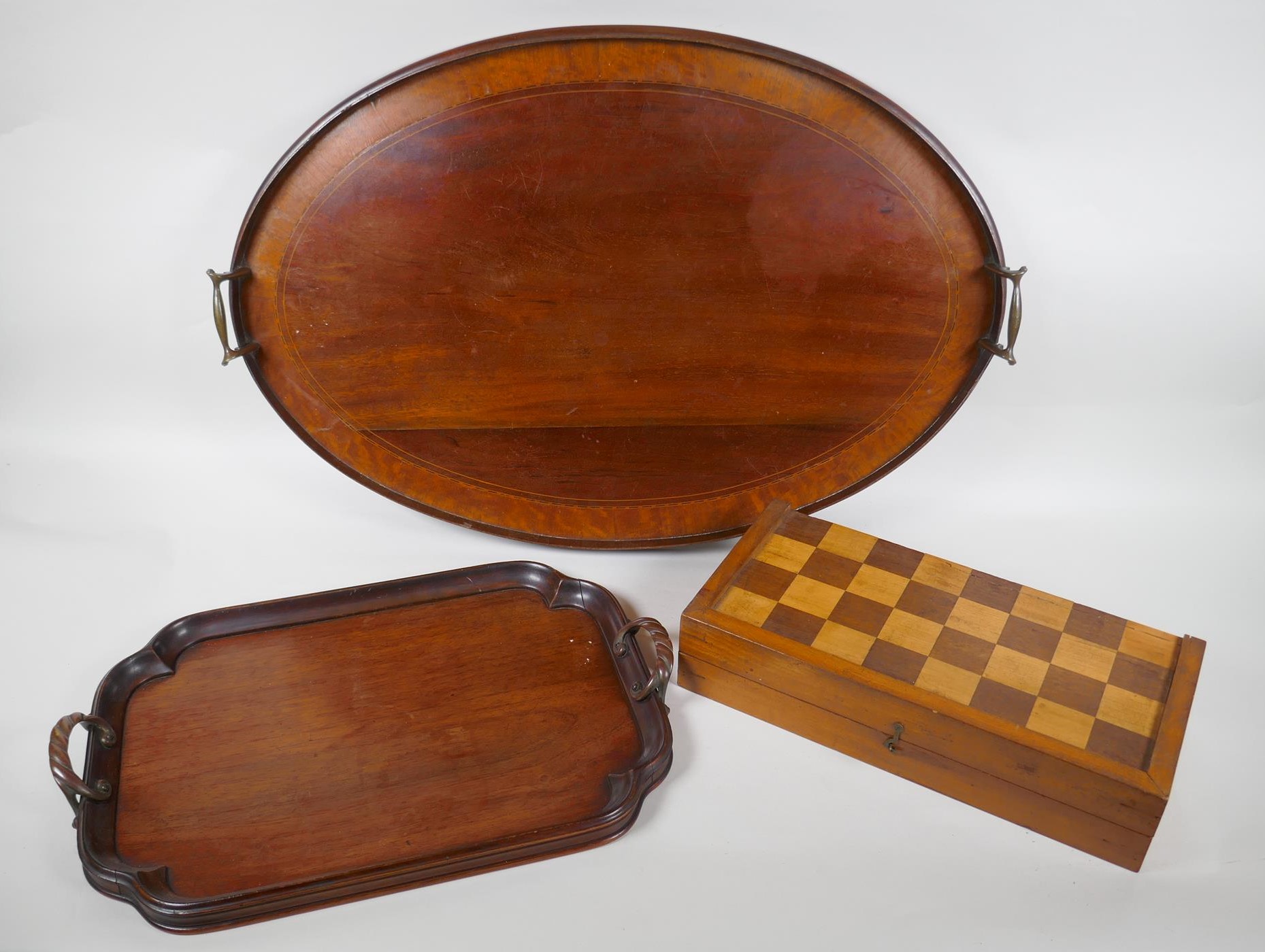 An antique inlaid mahogany oval serving tray, a smaller mahogany serving tray and a chess board,