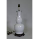 A white glazed porcelain table lamp in the form of an oriental vase, with brass mount and carved