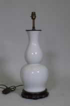 A white glazed porcelain table lamp in the form of an oriental vase, with brass mount and carved