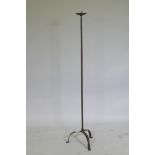 A wrought iron floor standing pricket candlestick on tripod supports, 128cm high
