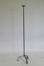 A wrought iron floor standing pricket candlestick on tripod supports, 128cm high