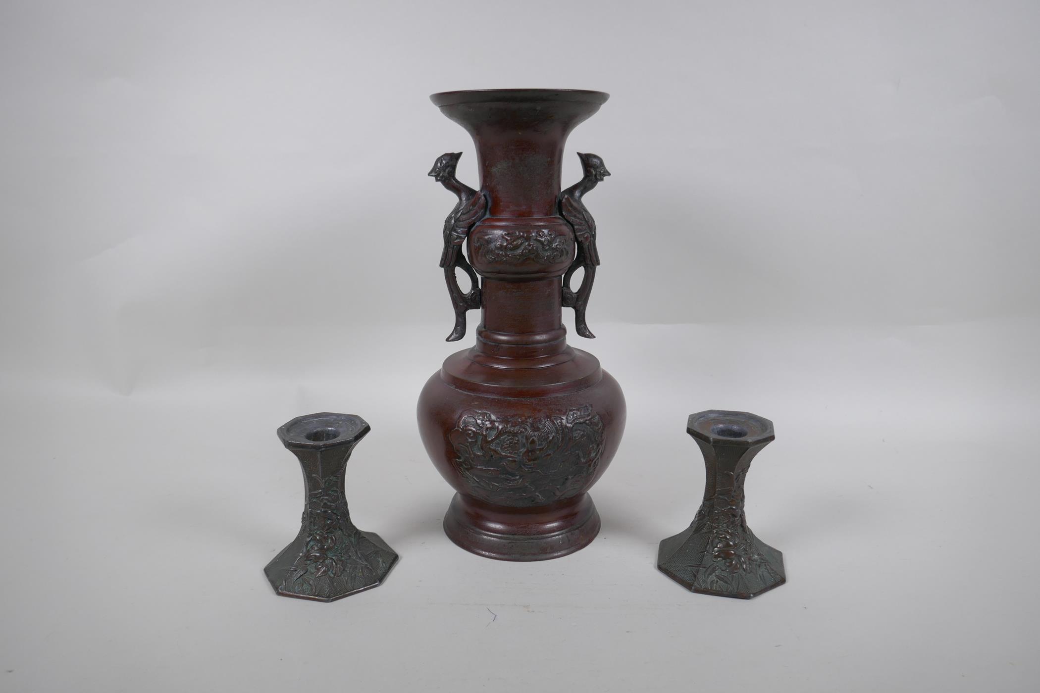 A pair of early C20th Japanese bronze candlesticks of hexagonal waisted form, with raised floral