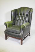 A Georgian style button back leather wing armchair with brass stud decoration