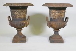 A pair of cast iron garden urns with two mask handles and raised decorative frieze, 60cm high