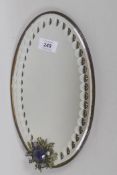 A small antique mirror with bevelled and cut glass and applied ornament set with paste stones,